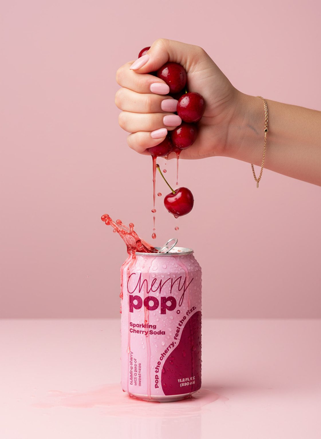 Cherry Pop hand squeezing fresh cherries over an open can of sparkling cherry soda