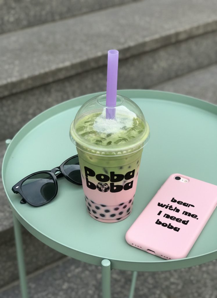 Poba Boba matcha bubble tea on a mint side table with sunglasses and a branded phone case