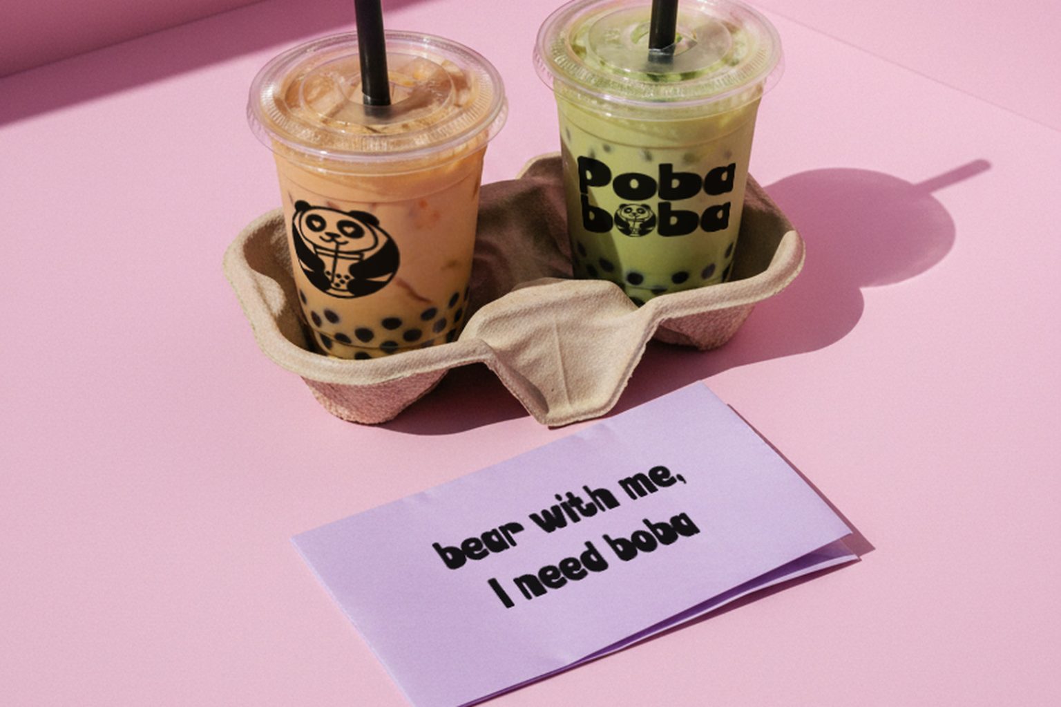 Poba Boba two bubble tea cups and a tagline card on a pink studio set